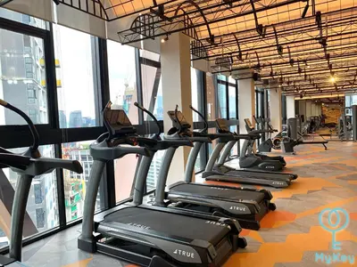 a row of treadmills in a gym with windows at Scarletz Suites KLCC by MyKey in Kuala Lumpur