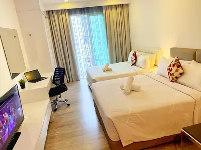 a hotel room with two beds and a flat screen tv at Lila Suites One Bukit Ceylon in Kuala Lumpur