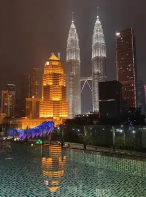 a view of a city skyline at night with a pool at 3 Bedrooms Short Stays Condo at KLCC in Kuala Lumpur