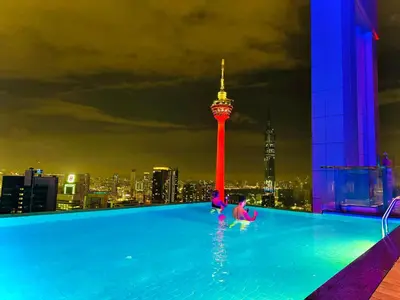 a couple of people in a swimming pool with a tower at Platinum KLCC By Rainbow Suites in Kuala Lumpur