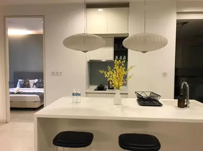 a kitchen with a counter with two stools and two lights at Platinum KLCC By Rainbow Suites in Kuala Lumpur