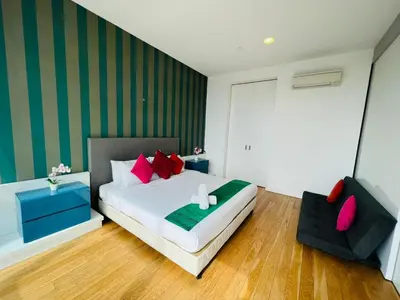 a bedroom with a bed with red pillows and a chair at Platinum KLCC By Rainbow Suites in Kuala Lumpur