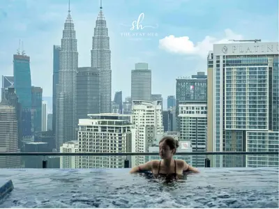 a woman in a hot tub with a view of the city at The Luxe & Colony KLCC Skyline Infinity Pool - 5min to Petronas Tower & KL City Center by The Stay Hub in Kuala Lumpur