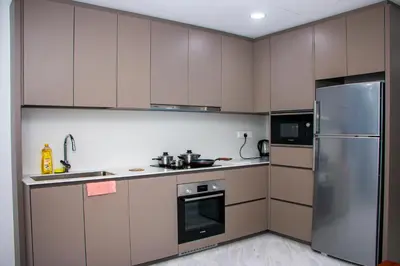 a kitchen with brown cabinets and a stainless steel refrigerator at Eaton Residence KLCC in Kuala Lumpur