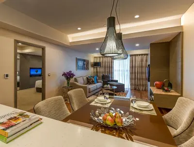 a kitchen and living room with a table and chairs at Ascott Sentral Kuala Lumpur in Kuala Lumpur
