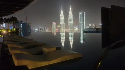 a row of benches with the kuala lumpur skyline at night at Eaton Residence KLCC by Yemala in Kuala Lumpur
