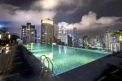 a swimming pool with a city skyline at night at Maxhome Plus at Dorsett Bukit Bintang in Kuala Lumpur