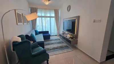 a living room with two blue chairs and a television at Aldridge Residence Coastal KLCC in Kuala Lumpur