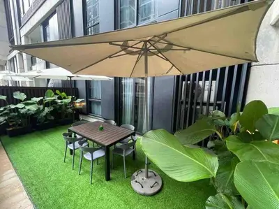 a patio with a table and chairs and a large umbrella at New Arcoris Mont Kiara Huge Balcony for 8 pax 2 BR -Garden- in Kuala Lumpur