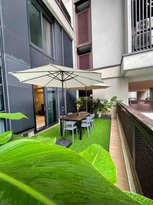 a patio with a table and chairs and an umbrella at New Arcoris Mont Kiara Huge Balcony for 8 pax 2 BR -Garden- in Kuala Lumpur