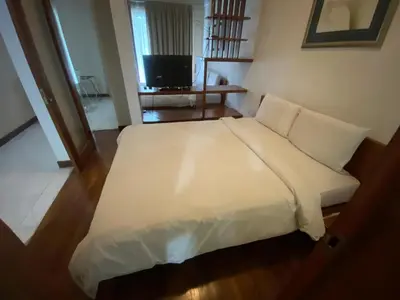 a white bed in a room with a television at Peninsula Residences All Suite Hotel in Kuala Lumpur