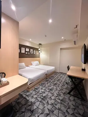 a hotel room with two beds and a desk at Hotel Damai Kuala Lumpur in Kuala Lumpur
