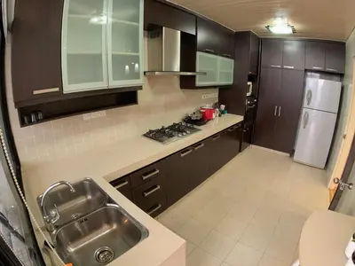 a kitchen with brown cabinets and a sink and a refrigerator at Bukit Bintang Fahrenheit88 Apartment by Sarah's Lodge in Kuala Lumpur