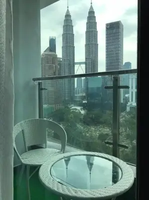 a balcony with a table and chairs and a view of a city at KLCC VIEW-3 BED LOVELY APARTMENTS IN KUALA LUMPUR in Kuala Lumpur