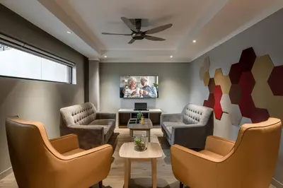 a living room with two chairs and a tv at Domitys Bangsar Kuala Lumpur in Kuala Lumpur