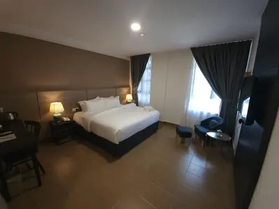 a hotel room with a white bed and a desk at Yu Hotel Chinatown in Kuala Lumpur