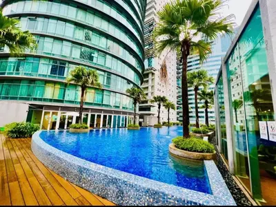 a large building with a pool in front of it with palm trees at VortexLuxApartman KLCC, kuala lampur city in Kuala Lumpur