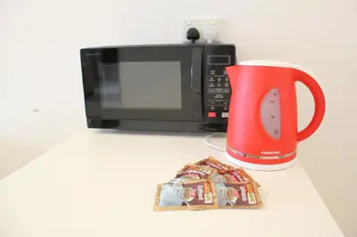 a red coffee mug next to a microwave and a pile of candy at Central 2BR Apt 5 mins to KLCC Twin Towers in Kuala Lumpur