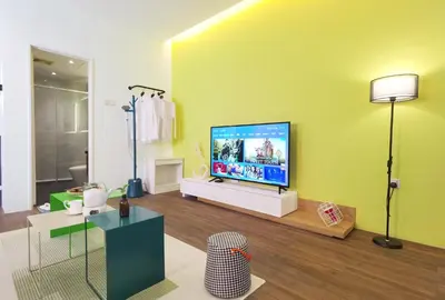 a living room with a flat screen tv on a yellow wall at The Territory @ Bangsar South Mid Valley in Kuala Lumpur