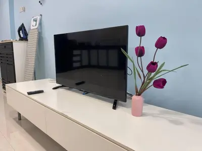 a tv sitting on top of a white table with purple flowers at Dalamanda 3Pax Sunway Velocity Balcony CItyView in Kuala Lumpur