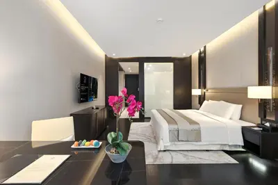 a bedroom with a bed and a table with a flower at Banyan Signatures Pavilion Kuala Lumpur in Kuala Lumpur
