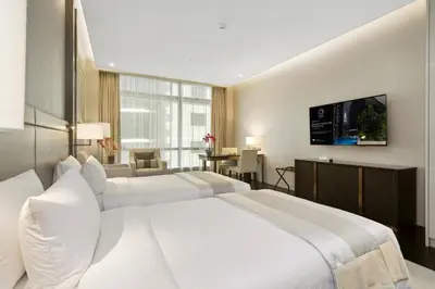 a bedroom with two white beds and a flat screen tv at Banyan Signatures Pavilion Kuala Lumpur in Kuala Lumpur
