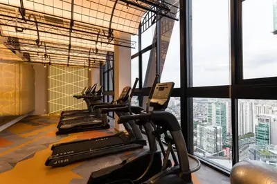 a row of treadmills in a gym with windows at Scarletz KLCC Studio Suites 4 pax Luxury Modern Style WiFi 100Mbps in Kuala Lumpur