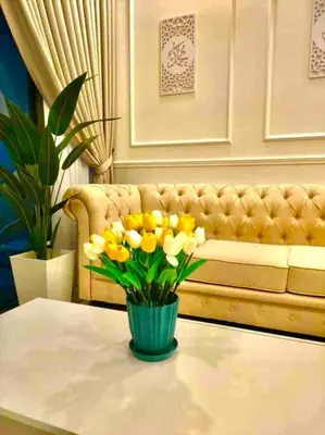 a vase of yellow flowers on a table with a couch at Millerz Suite 3R2B Condo Near MidValley 3 Beds 3 Bedrooms Staycation Best Choice in Kuala Lumpur