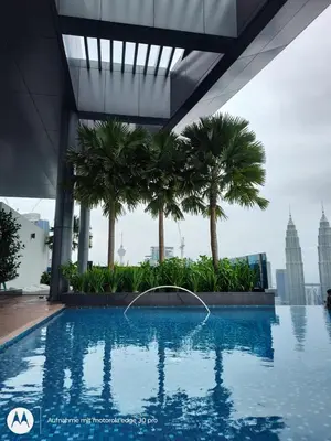 a swimming pool in a building with palm trees at Eaton suites KLCC at KL in Kuala Lumpur