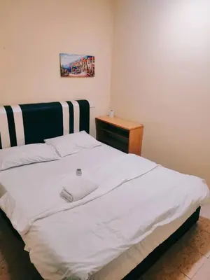 a large white bed in a room with a table at RAS Hotel in Kuala Lumpur