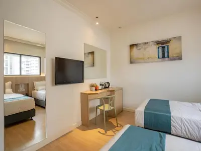 a hotel room with two beds and a desk with a television at Floresta Hotel Chinatown in Kuala Lumpur