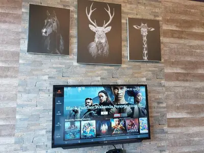 a flat screen tv on a stone wall with pictures at Romantic Log Cabin - walk to KL Tower, KLCC, Bukit Bintang in Kuala Lumpur