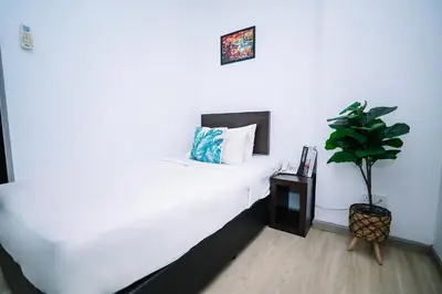 a bedroom with a white bed and a potted plant at Swing & Pillows - Dataran Merdeka Kuala Lumpur in Kuala Lumpur