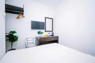 a white bedroom with a bed and a desk and a tv at Swing & Pillows - Dataran Merdeka Kuala Lumpur in Kuala Lumpur