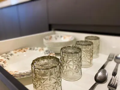 a table with glasses and plates and utensils on it at Skyline Garden 2 Bedrooms Homestay Near KLCC in Kuala Lumpur