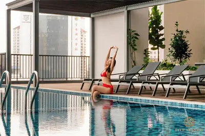 a woman in a bikini sitting next to a swimming pool at Chambers Residence Kuala Lumpur by Roam in Kuala Lumpur