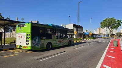 a green bus driving down a city street at Homestay Jalan Tun Razak walking distance IJN, HKL, MRT Raja Uda, PUSRAWI, KPJ, PERKESO, Istana Budaya Гостевой дом Куала-Лумпур โฮมสเตย์ กัวลาลัมเปอร์ in Kuala Lumpur