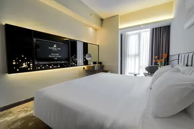 a bedroom with a white bed and a flat screen tv at Sleeping Lion Suites in Kuala Lumpur
