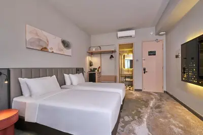 a hotel room with two beds and a television at Sleeping Lion Suites in Kuala Lumpur