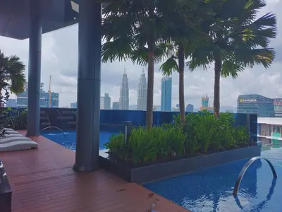 a swimming pool with palm trees and a city skyline at Eaton Residence KLCC Skyline in Kuala Lumpur