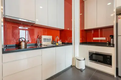 a kitchen with white cabinets and red walls at Arcoris Mont Kiara in Kuala Lumpur