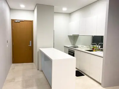 a kitchen with white cabinets and a brown door at Sky Suites KLCC by PNUT in Kuala Lumpur
