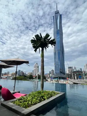 a pool with a palm tree and a tall building at Opus Residences KL Malaysia in Kuala Lumpur