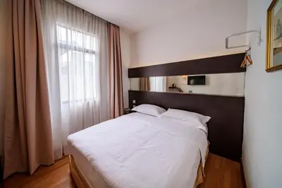 a bedroom with a large bed with white sheets and a window at Uptown Chinatown in Kuala Lumpur