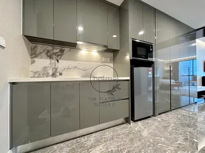 a kitchen with gray cabinets and a counter with a refrigerator at The Platinum 2 Kuala Lumpur by HOLMA in Kuala Lumpur