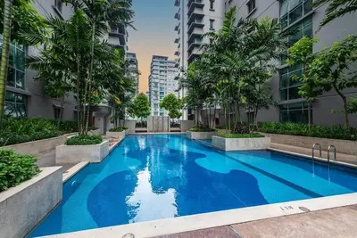 a large blue swimming pool in a building with palm trees at MITEC Publika 500Mbp Wi-fi Studio Mont Kiara Hartamas in Kuala Lumpur