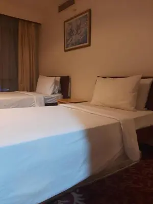 a hotel room with two beds with white sheets at Times Square East privite service Apartment in Kuala Lumpur