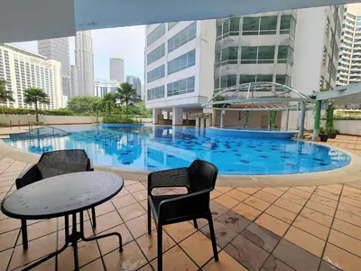 a swimming pool with two chairs and a table in front of a building at Crest Residence Klcc Bukit Bintang by Sarah's Lodge in Kuala Lumpur