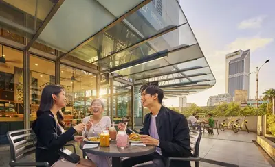 three people sitting at a table outside a restaurant at S36- Robertson at Bukit Bintang 3 Bedroom with Netflix in Kuala Lumpur