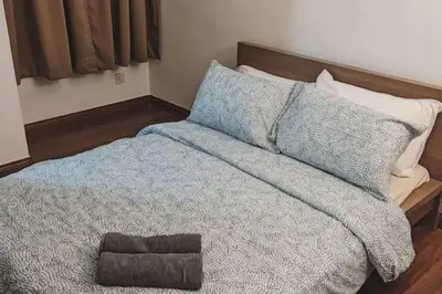 a bedroom with a bed with a blue blanket and pillows at 1 min Next to LRT CHERAS 68 in Kuala Lumpur